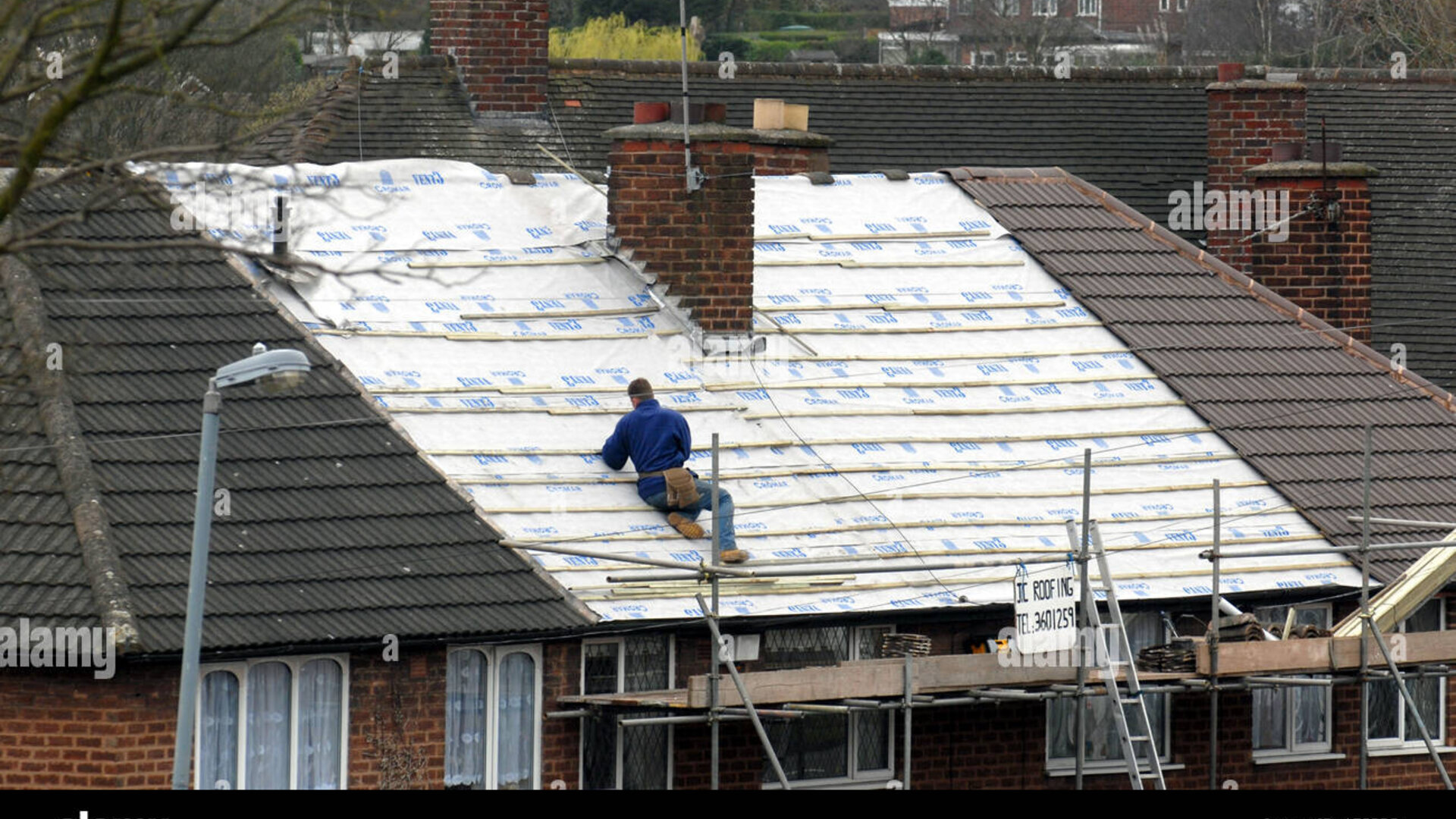 Roofer working on house roof